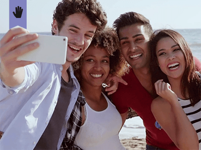 two couples at the beach taking a group selfie